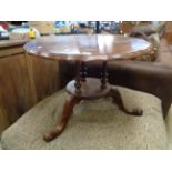 Shaped top carved circular table on turned supports above tripod legs