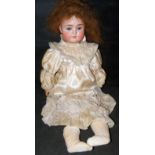 An old German bisque head doll with rolling eyes and open mouth, having composite body and
