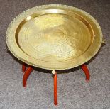 An oriental foldable brass topped table, lacquered in red with brass covered legs. CONDITION REPORT: