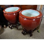 A Pair of 20th Century Chinese Large Jardinieres with a rouge glaze upon shaped hardwood stands,