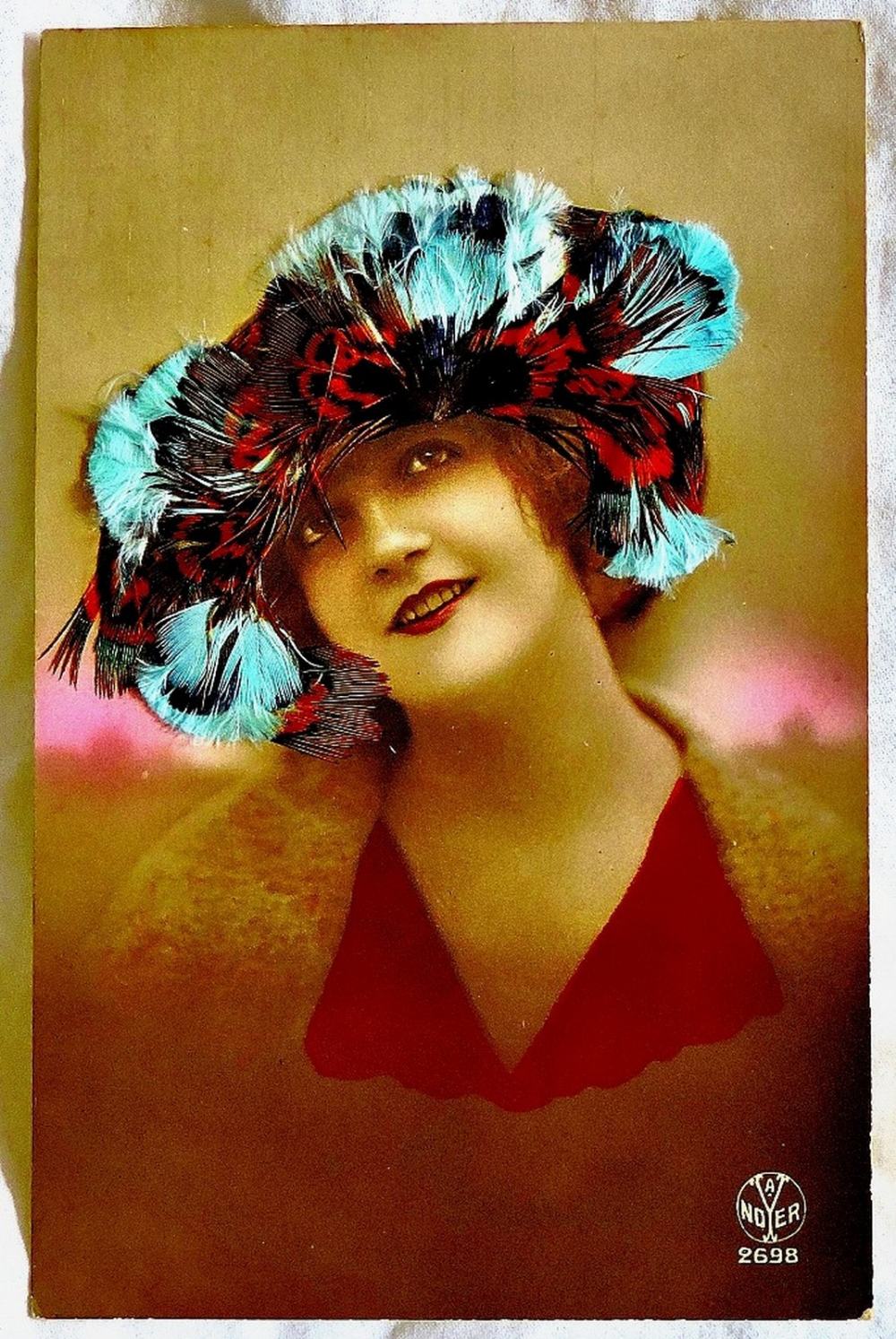 Millinery  A beautiful lady with a fine hat and  created on a postcard in radiant bird feathers.