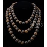 AGARWOOD BEAD NECKLACE. In brown silk storage box. SIZE: Total: 28" l. Largest bead: 1-1/8" dia.