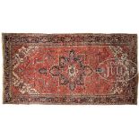 SEMI-ANTIQUE PERSIAN HERIZ CARPET. This long narrow carpet has a large bold center medallion on a