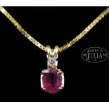 RUBY AND DIAMOND PENDANT ON A 14KT YELLOW GOLD NECKLACE. The pendant having an oval ruby of