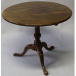 A GEORGE III MAHOGANY CIRCULAR TILT TOP TRIPOD TABLE with solid top, turned centre column on pad