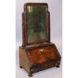 AN EARLY 18TH CENTURY WALNUT TOILET MIRROR with shaped bevelled mirror over a fall enclosing small