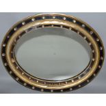 A REGENCY OVAL WALL MIRROR, Possibly IRISH, with cut glass mounted, ebonised and gilded frame 1ft