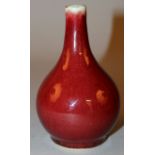 A 20TH CENTURY CHINESE SANG-DE-BOEUF PORCELAIN BOTTLE VASE, the sides applied with a lightly