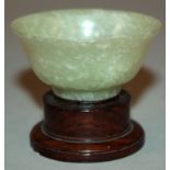 AN EARLY 20TH CENTURY CHINESE JADE-LIKE CELADON GREEN WINE CUP, with a wood stand, the stone with