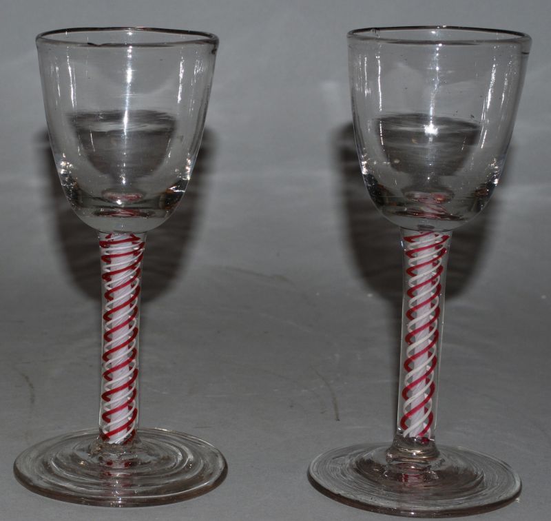 A VERY NEAR PAIR OF 18TH CENTURY WINE GLASSES with red and white stems. 5.75ins high.