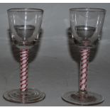 A VERY NEAR PAIR OF 18TH CENTURY WINE GLASSES with red and white stems. 5.75ins high.