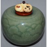 A SMALL GREEN PORCELAIN VASE with carved ivory cat finial. 2ins.