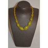 A CHINESE GREEN AMBER TYPE NECKLACE, with graduated beads.