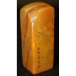 A CHINESE STONE SEAL, of amber tone, decorated in low relief with calligraphy and with sages in a