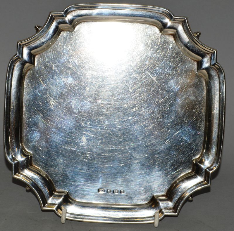 A SQUARE SILVER PIE CRUST SALVER, 7.5ins, supported on three pad feet. Sheffield 1956. Weight 10ozs.