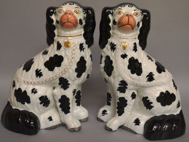 A GOOD PAIR OF BLACK AND WHITE STAFFORDSHIRE SEATED POODLES with orange eyes, green and gilt nose,