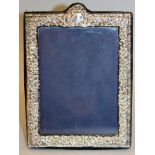 A REPOUSSÉ EASEL PHOTOGRAPH FRAME with foliate decoration. 7ins high x 5ins wide. London 1990.