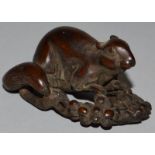 A CARVED WOOD NETSUKE, a rat on fruit.