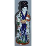 A JAPANESE PORCELAIN FIGURE OF A GEISHA in brilliant colours carrying a book. 14.5ins high.