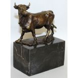 L. CORVIN A BRONZE COW. Signed. 5.5ins long, on a marble plinth.