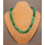 A CHINESE APPLE-GREEN JADEITE-LIKE NECKLACE, composed of spherical beads, the beads 0.5in