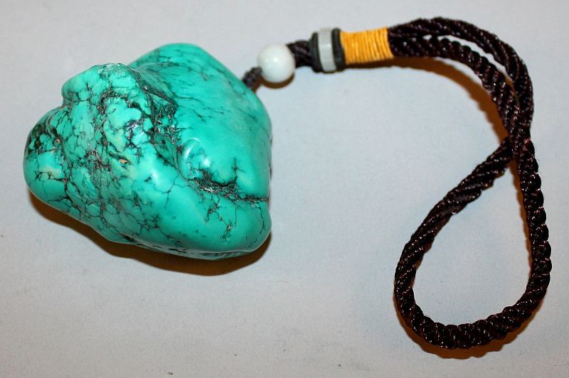 A CHINESE TURQUOISE-LIKE PENDANT, of boulder form, with attached tassel, the pendant 2.4in wide &