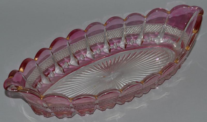AN OVAL RUBY TINTED DISH with hobnail cutting and star base.