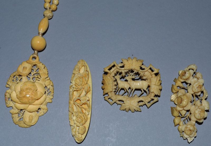AN IVORY CHAIN AND PENDANT AND THREE BROOCHES.
