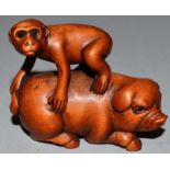 A BOXWOOD CARVED NETSUKE, A MONKEY ON A PIG’S BACK, signed.