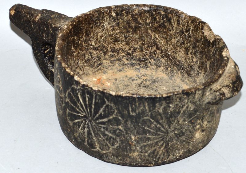 A VERY EARLY STONE CIRCULAR POT with handle and flower motifs to the side 6ins diameter.
