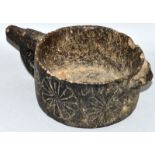 A VERY EARLY STONE CIRCULAR POT with handle and flower motifs to the side 6ins diameter.