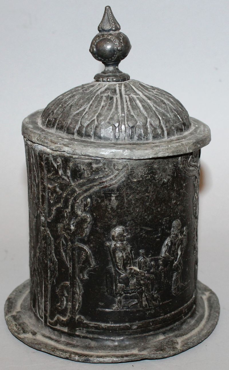 A CIRCULAR BOX AND COVER, the domed lid with finial, the sides with two men drinking wine. 5ins