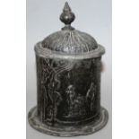 A CIRCULAR BOX AND COVER, the domed lid with finial, the sides with two men drinking wine. 5ins