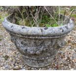 A RECONSTITUTED STONE WEATHERED GARDEN URN decorated with swags of flowers. 1ft 1ins high.