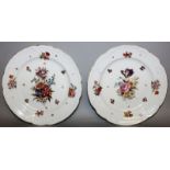 A PAIR OF CONTINENTAL CIRCULAR PLATES painted with flowers with raised scroll borders. 9ins