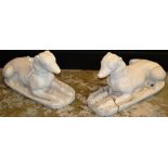 A pair of reconstituted and painted figures of reclining dogs