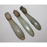 A GROUP OF THREE SIMILAR 19TH CENTURY CHINESE CELADON GREEN JADE BELT HOOKS, each hook carved in the