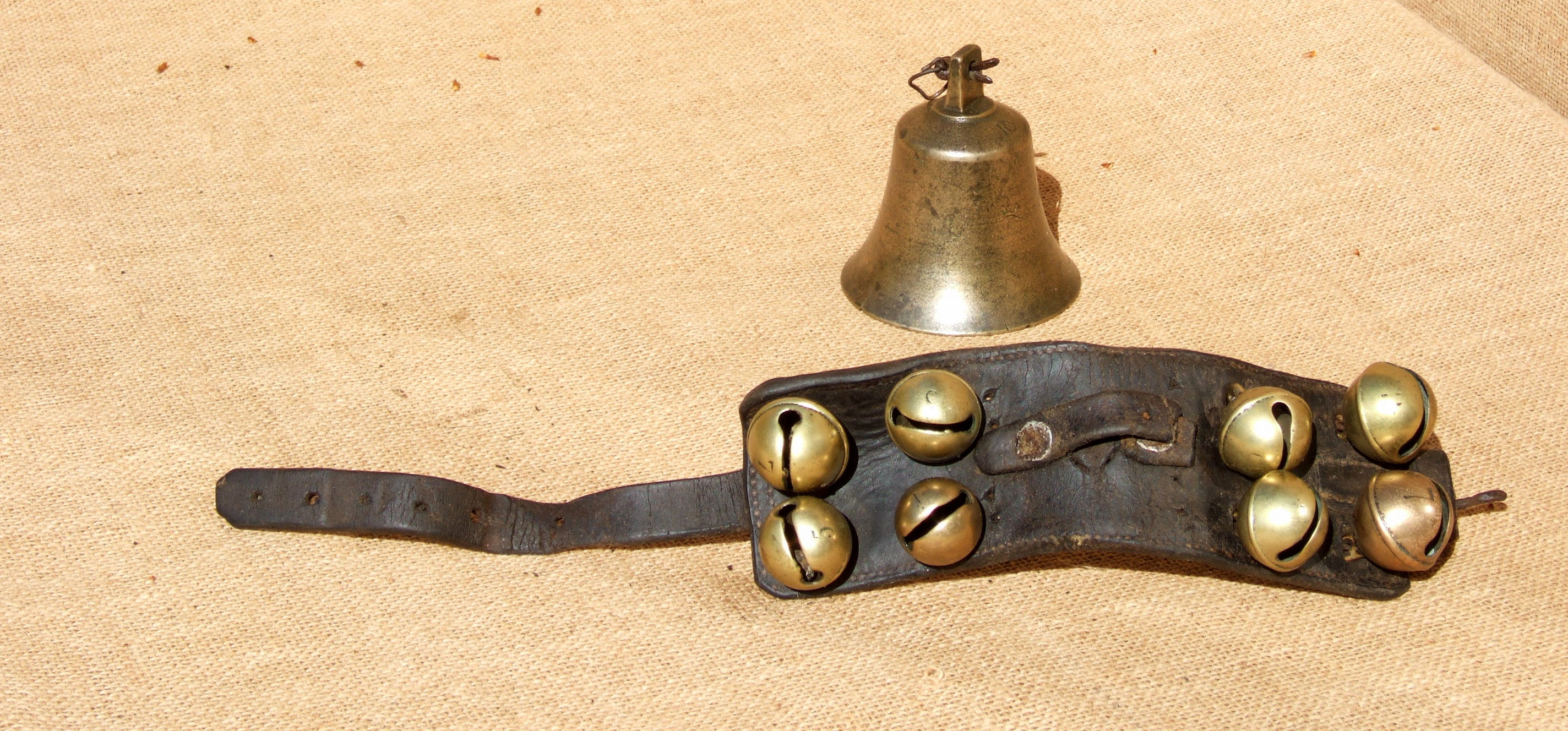 A LATTEN BELL AND EIGHT RUMBLER HARNESS BELLS. The 18th century latten bell is marked ‘RW’ and is