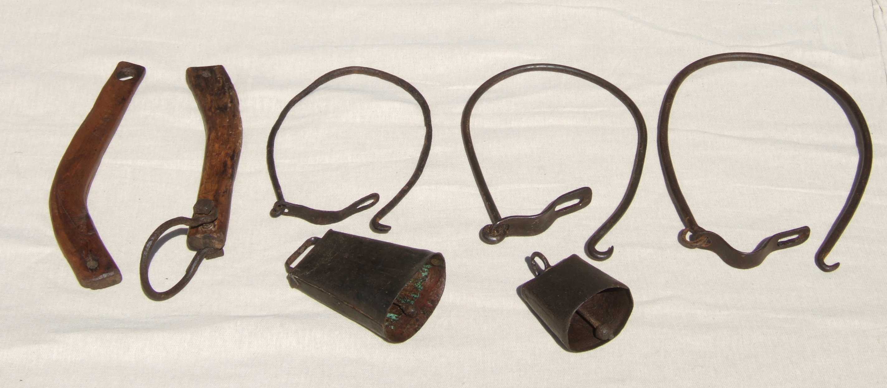 THREE IRON COW TETHERS, A CUMBRIAN TETHER AND TWO COW BELLS. Both bells are 18th century. One is