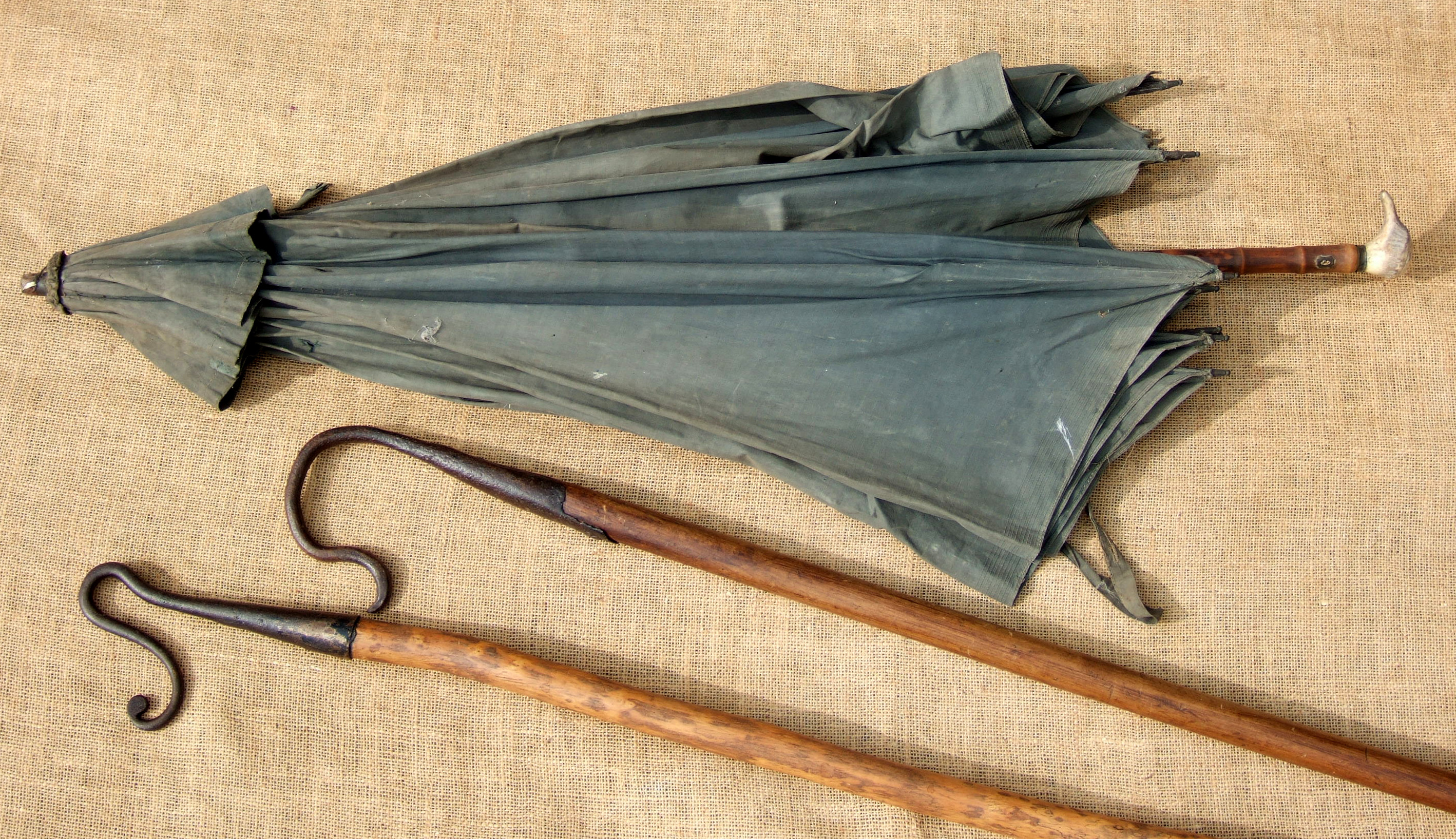 A SHEPHERD’S NECK CROOK, A LEG CROOK AND A RUSTIC UMBRELLA. The Sussex crooks are 19th century.