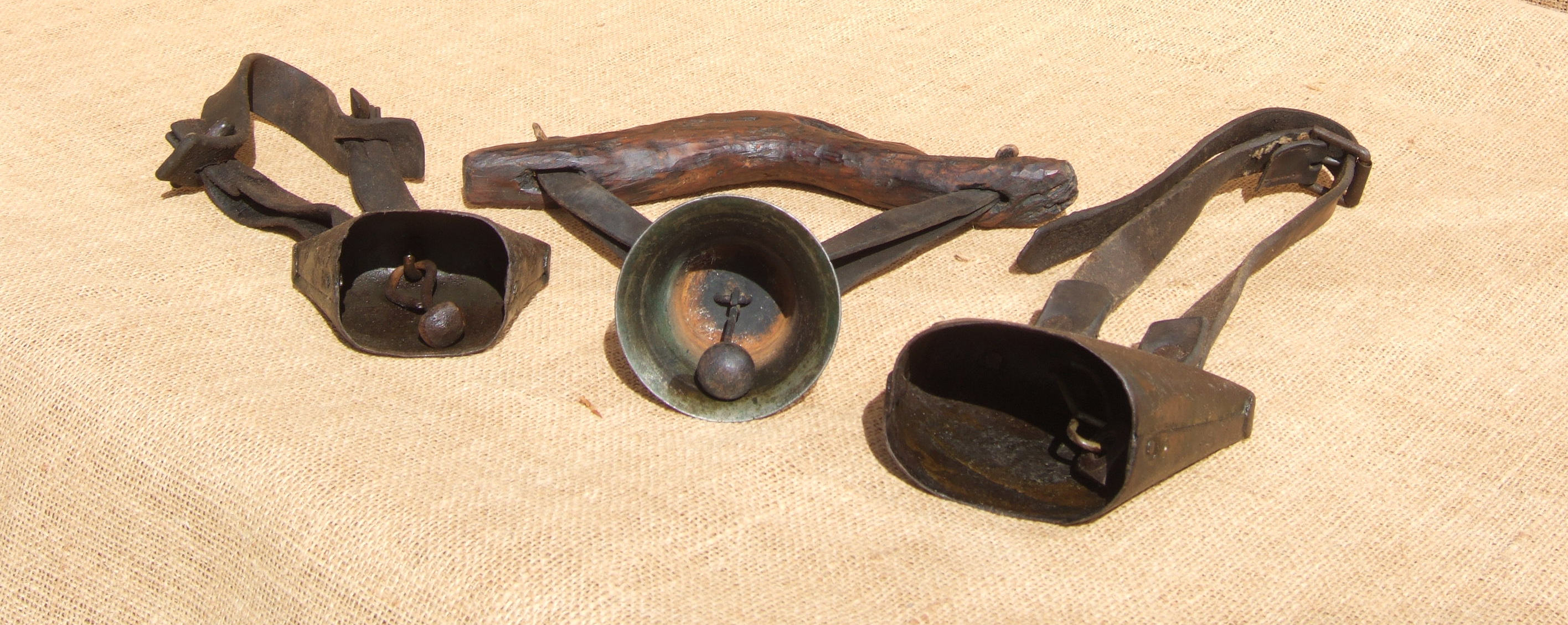 A LATTEN AND TWO CLUCKET SHEEP BELLS. The small clucket is on a leather strap, 18th century. The