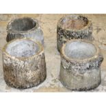 A SET OF FOUR RECONSTITUTED STONE PLANTERS modelled as tree  stumps 11ins high.