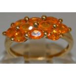 A TEN STONE ORANGE DRESS RING set in 9ct gold.