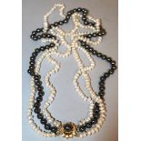 A TRIPLE ROW BLACK AND WHITE NECKLACE with gold clasp.