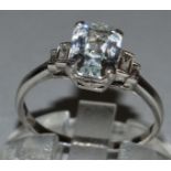 A GOOD WHITE SAPPHIRE AND DIAMOND RING set in platinum, baguette cut central white sapphire with