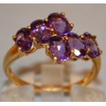 A SIX STONE AMETHYST CROSSOVER RING set in 9ct gold.