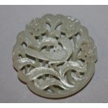 A DEEP CHINESE CELADON JADE SHAPED CIRCULAR PLAQUE, carved and pierced with a bird amidst flowers