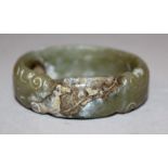 A CHINESE JADE BANGLE, carved in an archaic style with opposing dragons heads, 2.7in diameter, the