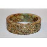 AN UNUSUAL CHINESE JADE BANGLE, 19th Century or earlier, the stone of underlying green tone with