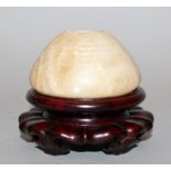 A CHINESE SHOUSHAN STONE SCHOLAR’S WATER POT, together with a wood stand, the beige stone with